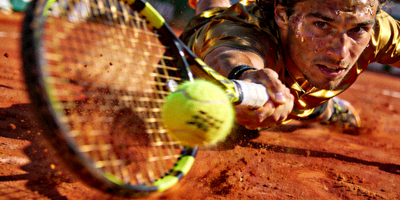 网球大满贯比赛，运动员在红土场上奋力击球的特写镜头